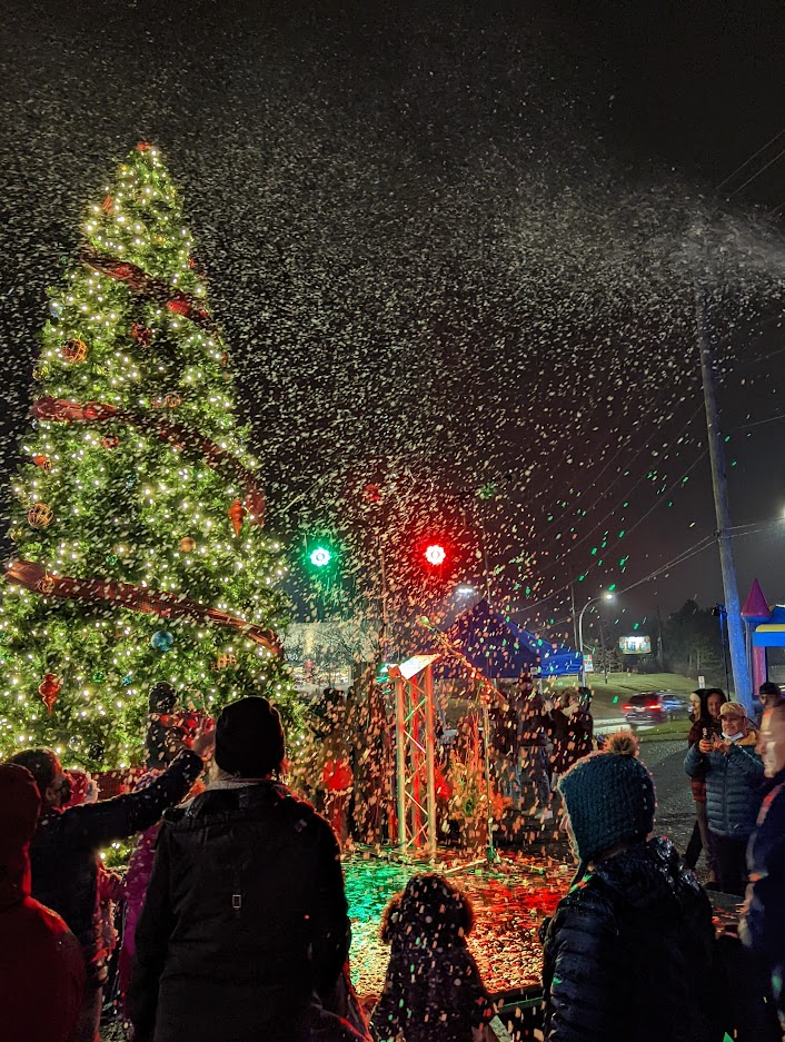 a group of people standing around a christmas tree.