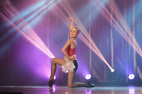 a young girl is dancing on a stage.
