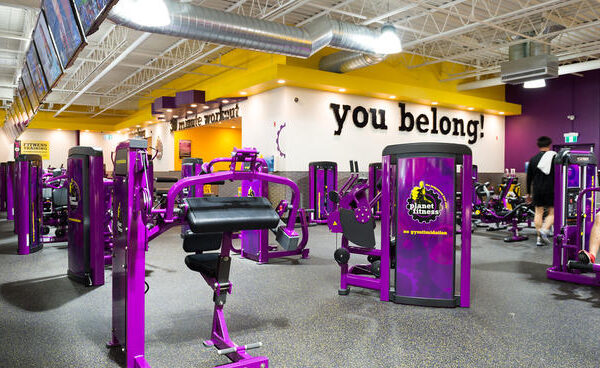 a gym filled with purple exercise equipment and people.