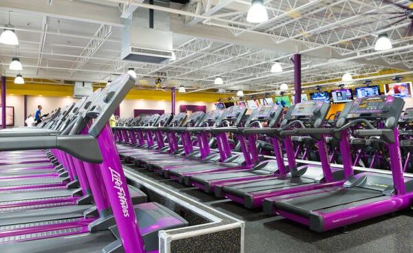 a row of purple treadmills in a gym.