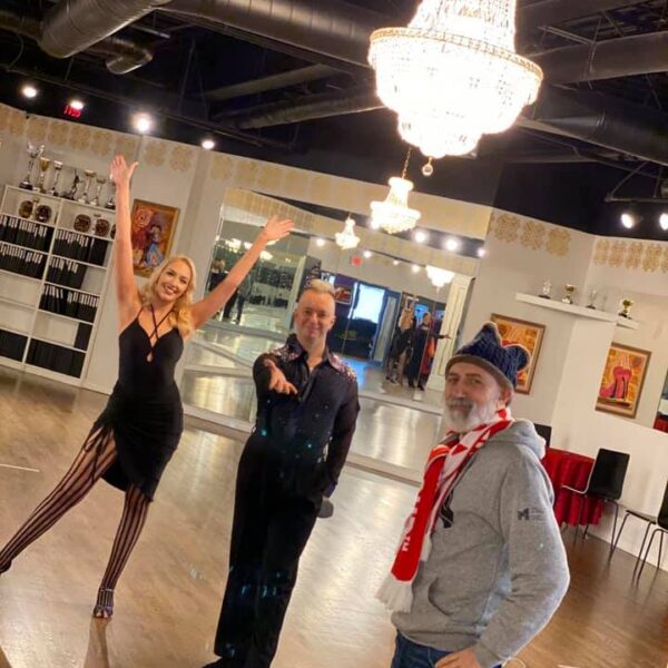 a group of people standing in dance studio with chandelier
