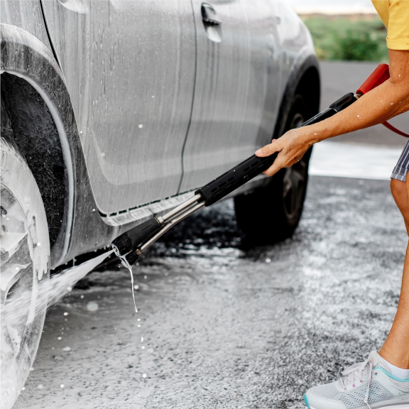 a person washing a car with a hose.
