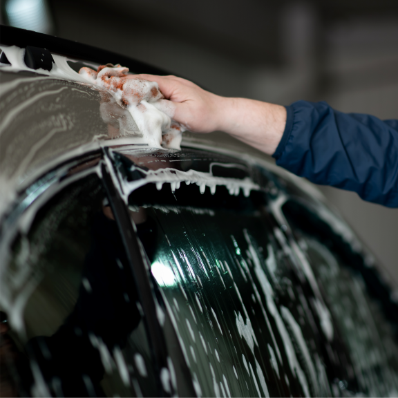 a person washing a car with a cloth.
