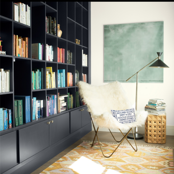 a chair in a room with a rug and bookshelves.