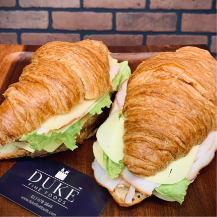 a croissant sandwich on a croissant with cheese and lettuce.