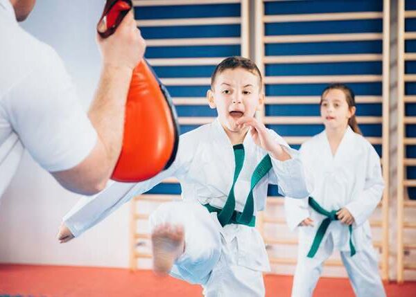 a young boy is practicing karate in a gym.