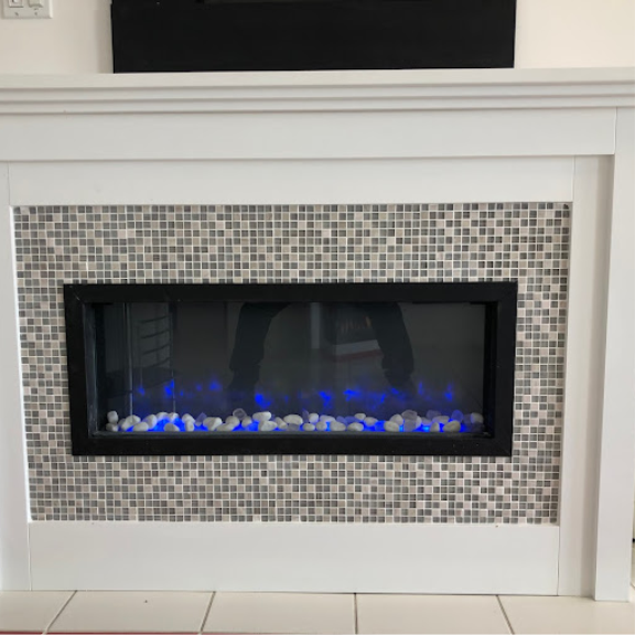 a white fireplace with a blue flame in it.