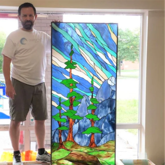 a man standing next to a stained glass window.