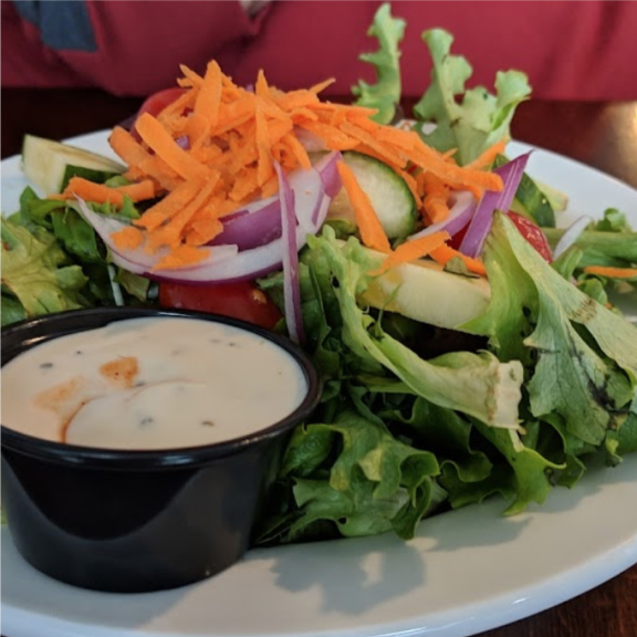a white plate topped with a salad and dressing.