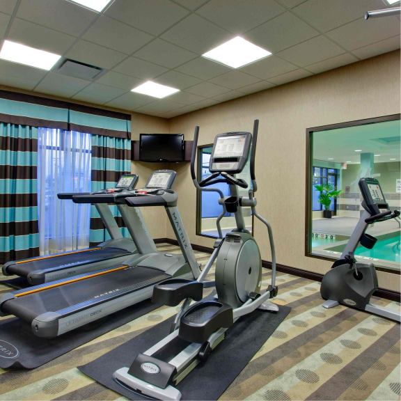 a gym with treadmills, exercise bikes, and a flat screen tv.