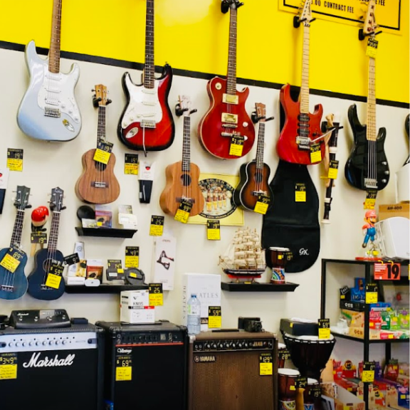 a wall full of guitars and amps in a store.
