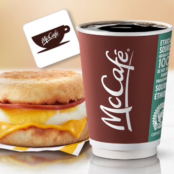 a cup of coffee next to a breakfast sandwich.