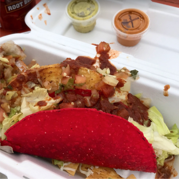 a plastic container filled with a taco covered in lettuce.