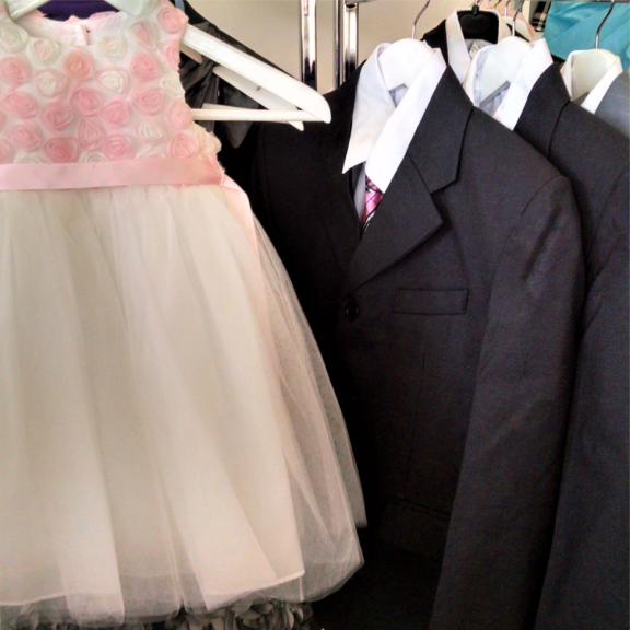 a little girl's dress and suit hanging on a rack.