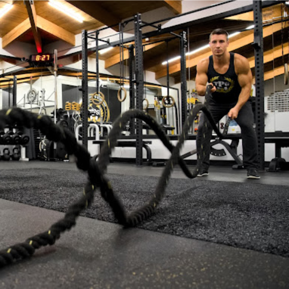 a man in a gym holding a battle rope.