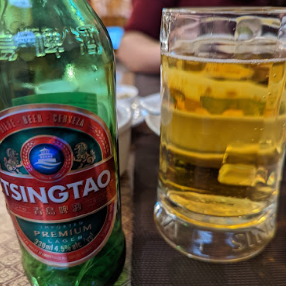 a bottle of tsingtao beer sitting next to a glass of beer.