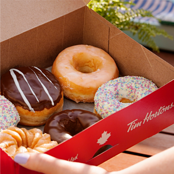 a box filled with assorted donuts on top of a wooden table.