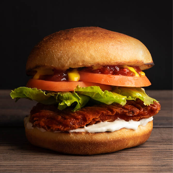 a chicken sandwich with lettuce, tomato, and mustard.