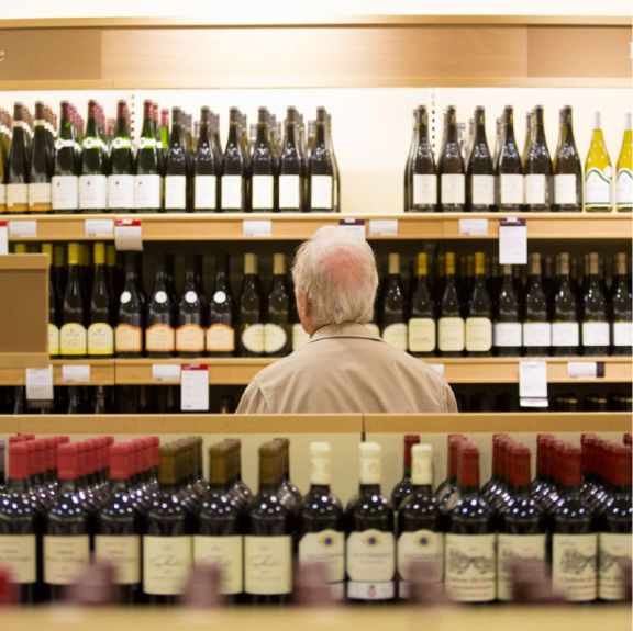 man contemplating rows of wine bottles
