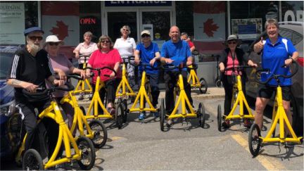 a dozen seniors using bright yellow walking bikes