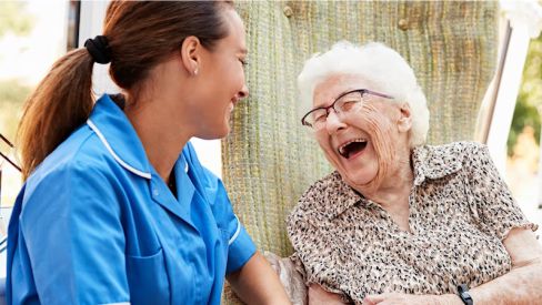 Old woman laughing with caregiver