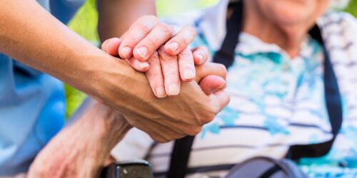 caregiver holding elderly person's hand
