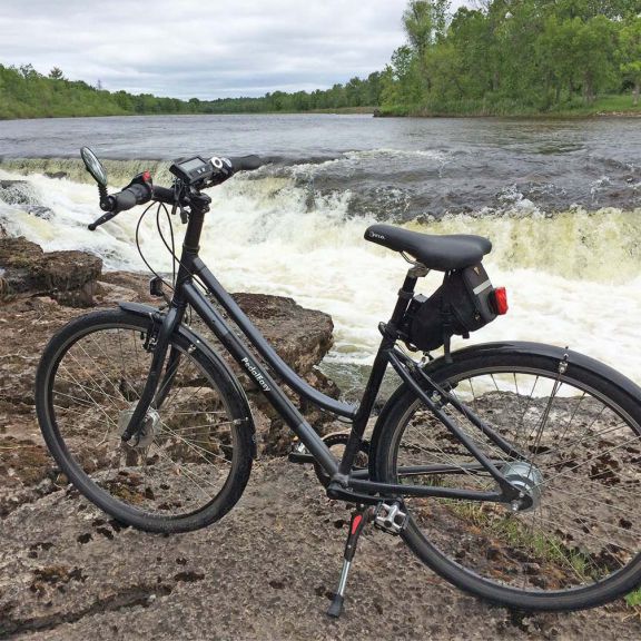 a bicycle parked on a rock near a river.