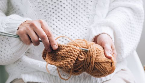 a woman knitting a ball of yarn with a crochet hook.