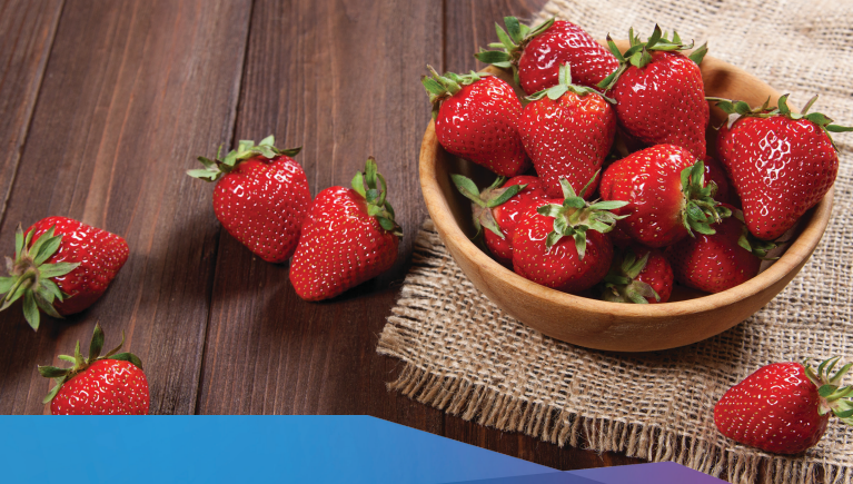 a bowl full of strawberries on a wooden table.