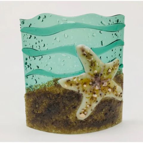 a glass candle holder with a starfish on it.