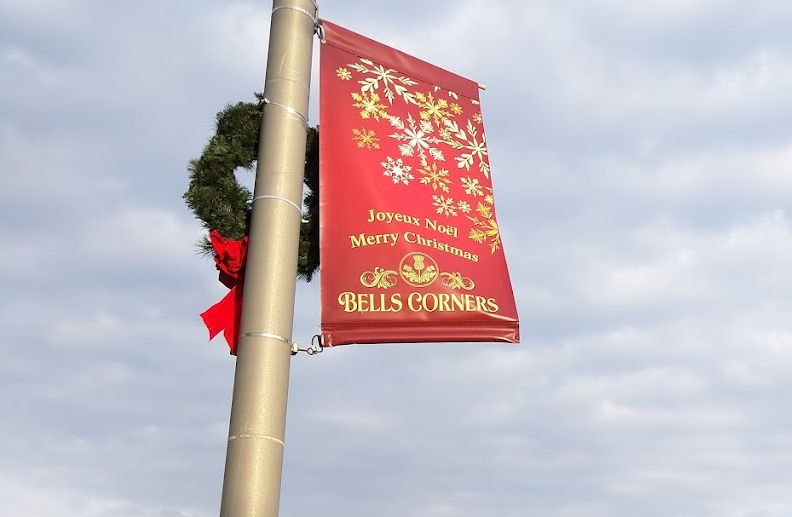a christmas banner on a pole next to a christmas tree.