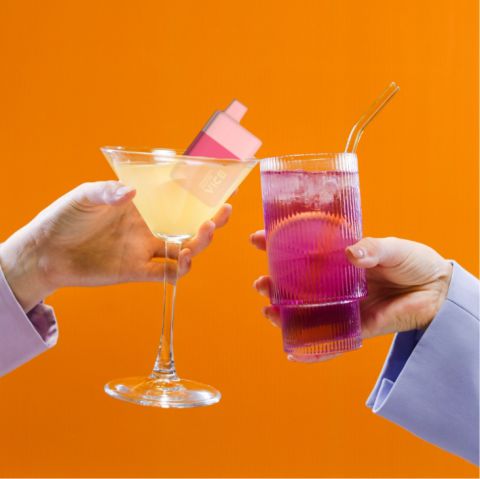 Two hands holding a drink with a straw on an orange background.