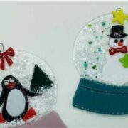 Two glass ornaments with penguins and snow globes.