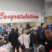 A group of people standing in front of a sign that says congratulations.
