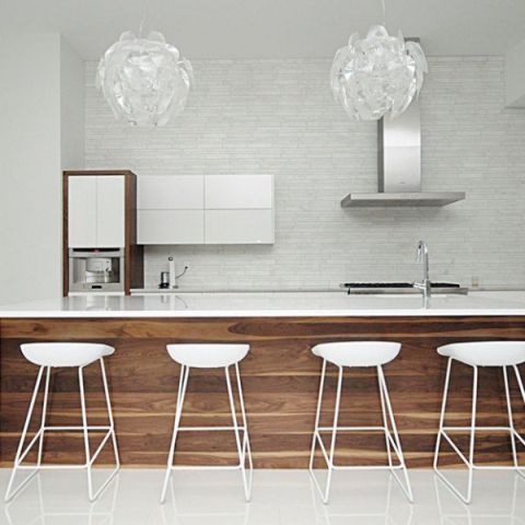 A modern kitchen with white counter tops and stools.