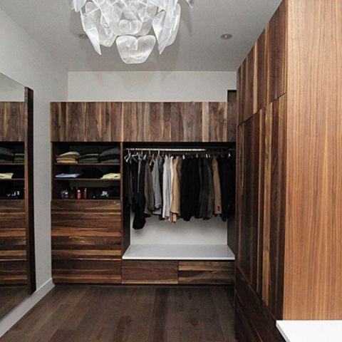 A walk in closet with wooden cabinets and a chandelier.