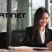 A woman working on a laptop in front of a fortinet logo.