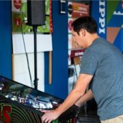 A man playing a pinball machine in a room.