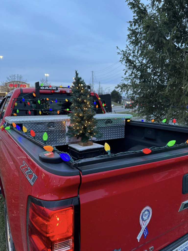 A red pickup truck with a christmas tree in the bed.