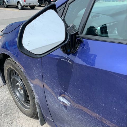 A blue car with a damaged rear view mirror.