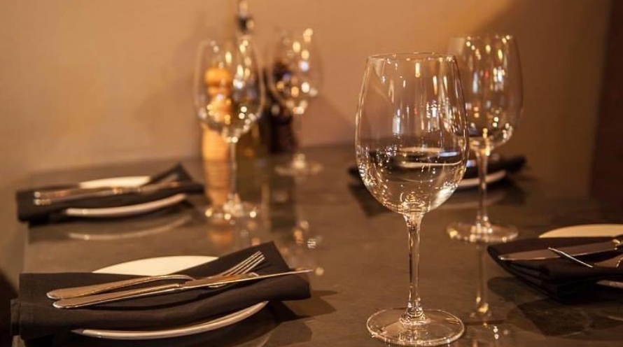 A table is set with wine glasses and silverware.