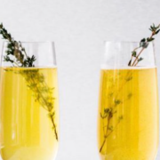 Two glasses of champagne with a sprig of thyme.