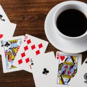 Playing cards and a cup of coffee on a wooden table.