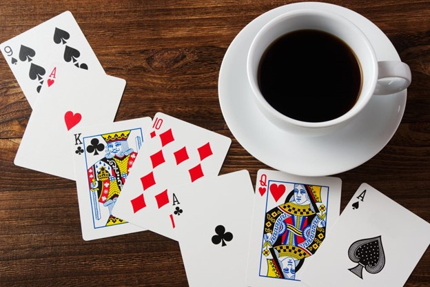 Playing cards and a cup of coffee on a wooden table.