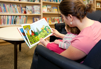 A woman reading a book to a child in a library.