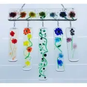 Five colorful glass wind chimes with floral designs hanging against a white background.